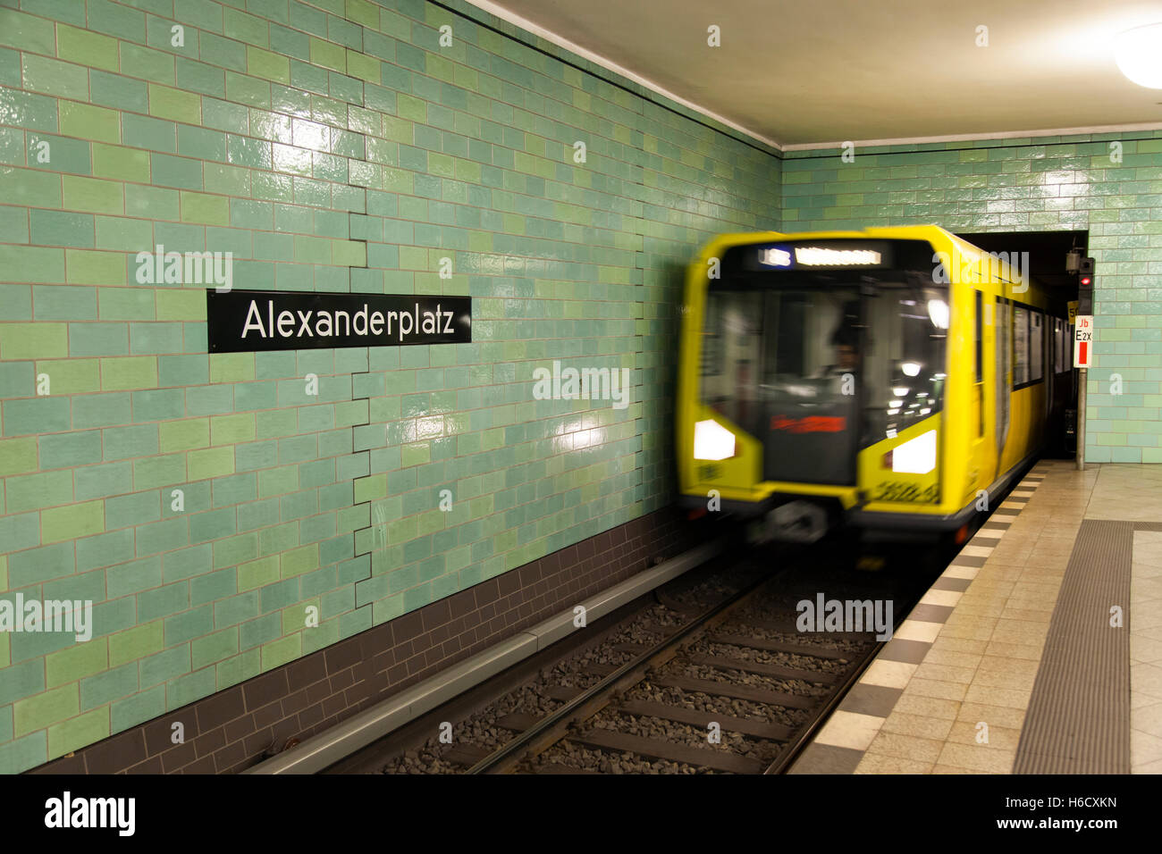 Sfocata motion view di un giallo treno arrivando alla piattaforma ad Alexanderplatz stazione della U-bahn a Berlino. Foto Stock