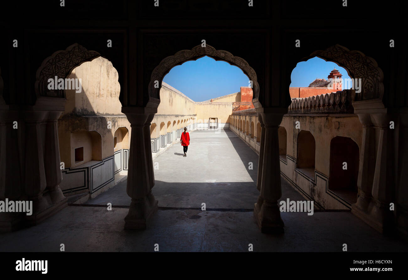 Donna in abito rosso a piedi nel palazzo Hawa Mahal con arch silhouette, Rajasthan, India Foto Stock