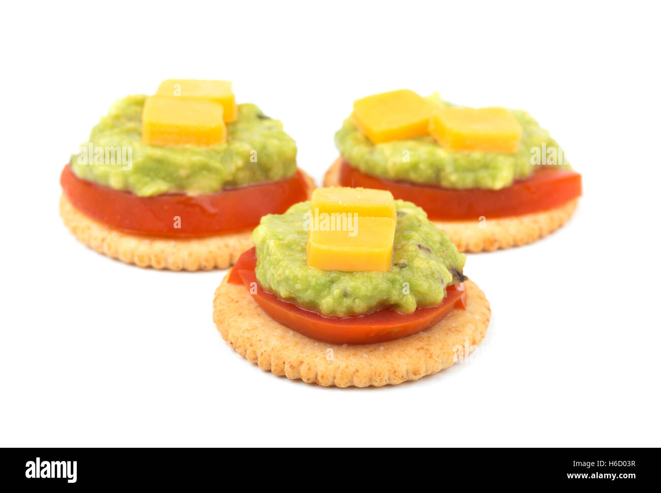 Grano intero crackers con pomodoro, guacamole e formaggio in cima, su bianco Foto Stock