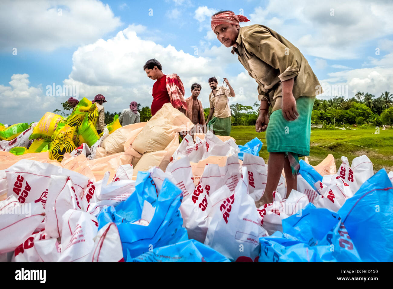 Gli uomini organizzano sacchi riempiti con pezzi di mattone per controllo di erosione di fiume in Bengala occidentale, India. Foto Stock