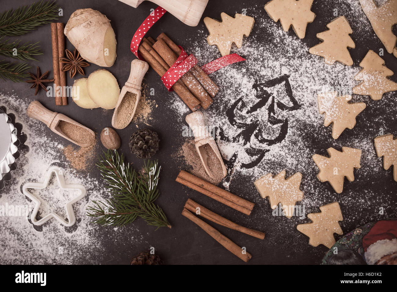 Telaio di cottura Ingredienti e pedaggi per pan di zenzero. Cookies e spezie su tavolo rustico con albero di Natale dipinto sulla farina Foto Stock