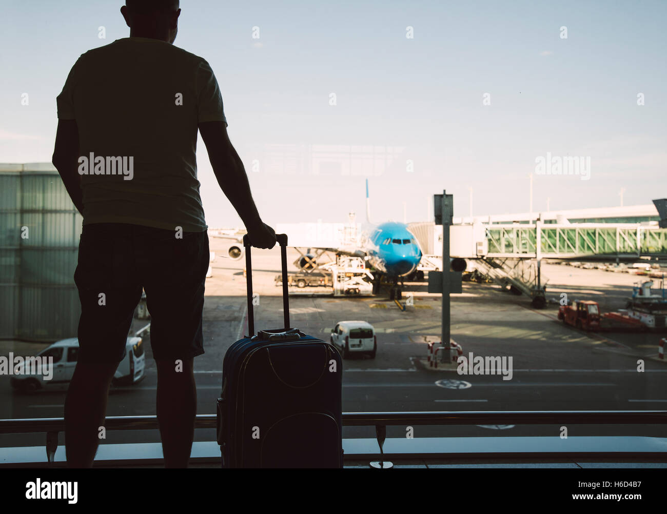 Silhouette di un uomo con una valigia in attesa di un volo all'aeroporto Foto Stock