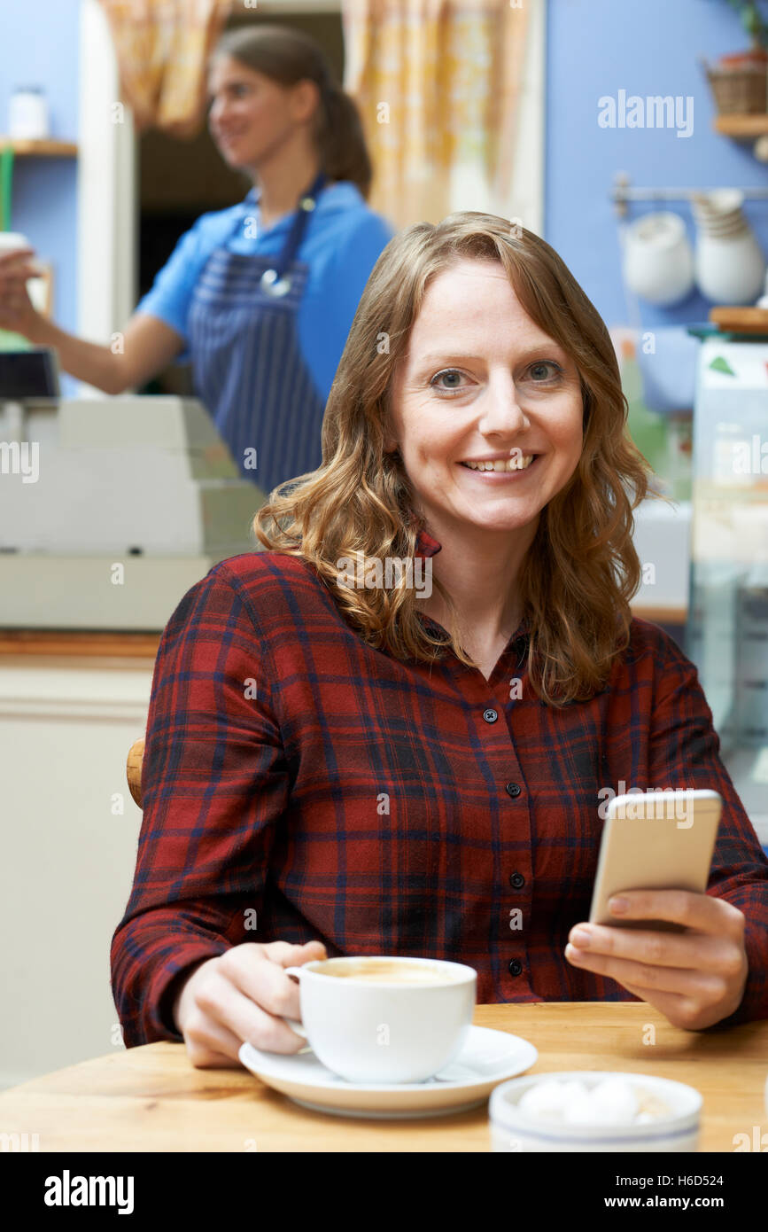 La donna nel Coffee Shop utilizzando il telefono cellulare Foto Stock