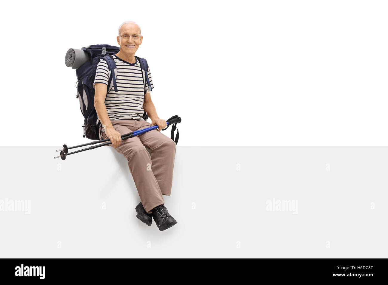 Gioioso escursionista maturo seduto su un pannello vuoto e guardando la telecamera isolata su sfondo bianco Foto Stock