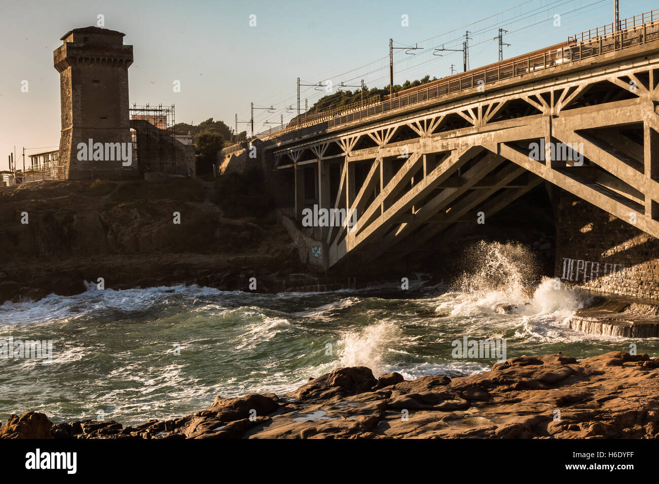 Torre sul promontorio vicino a Riva di linea e di onde che si infrangono sulla spiaggia rocciosa Foto Stock