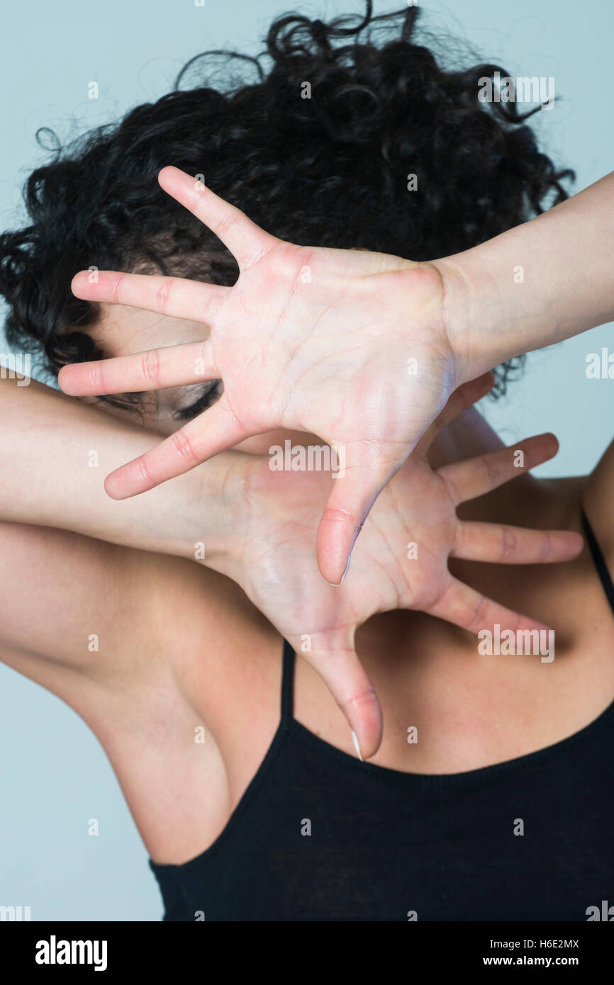 Spaventata giovane donna nasconde il viso con le mani nel timore Foto Stock