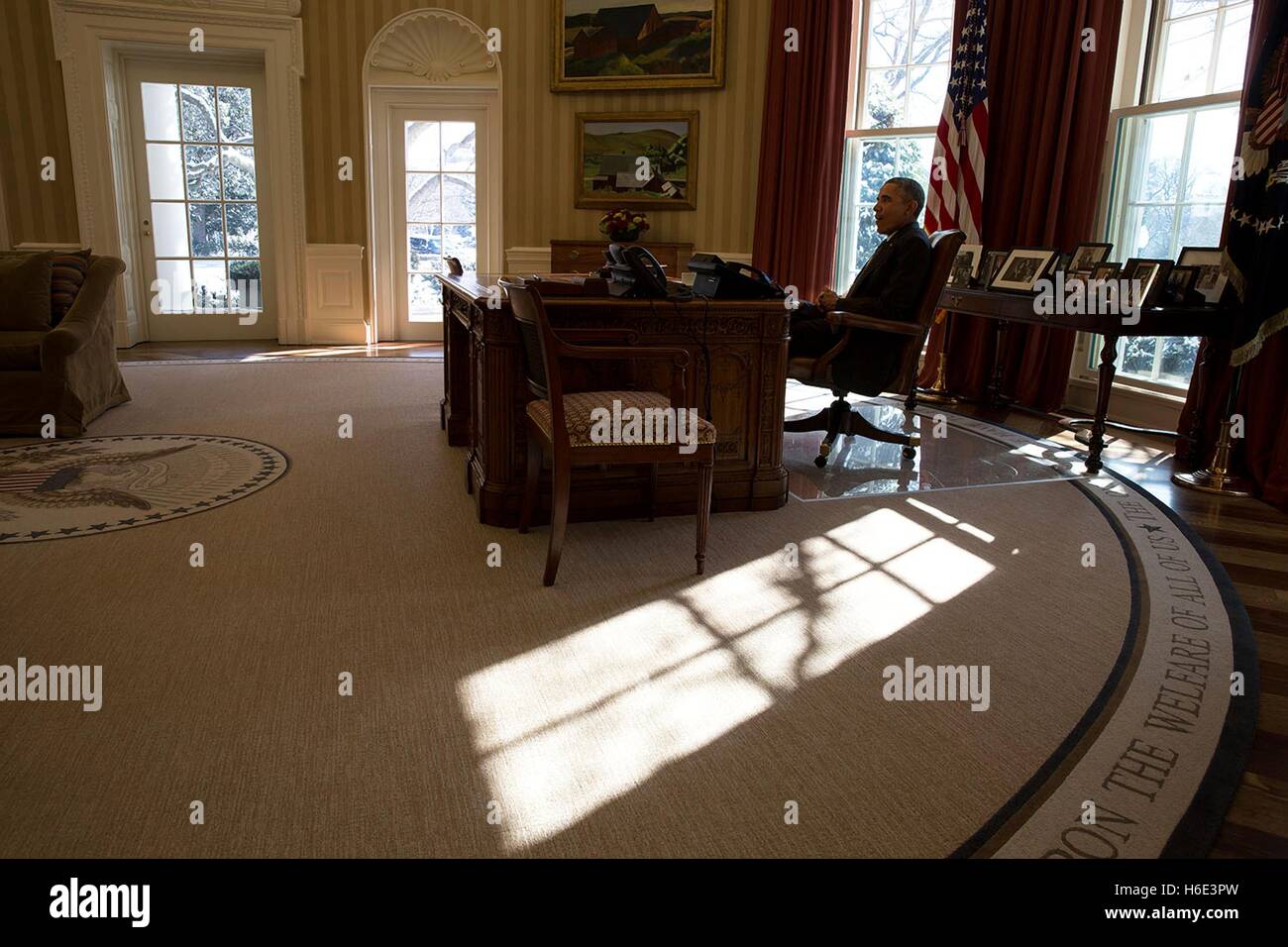Sun si riversa attraverso le finestre come U.S. Barack Obama presidente siede all Ufficio Ovale della Casa Bianca Resolute Desk Febbraio 17, 2015 a Washington, DC. Foto Stock
