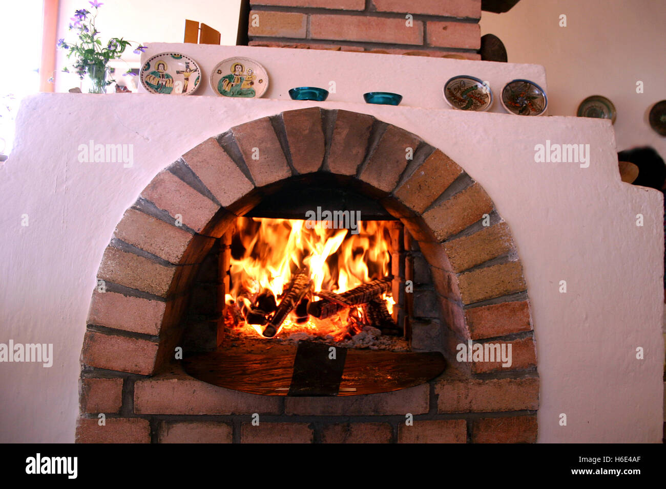 Legna da ardere in tradizionale forno di mattoni in cucina di campagna decorata con oggetti in ceramica tradizionali Foto Stock