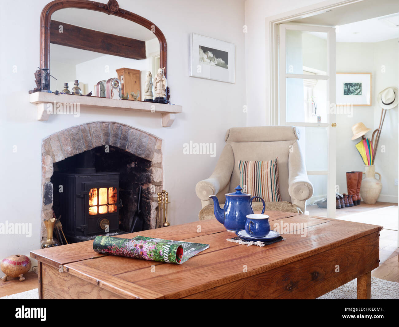 Un tavolino con una rivista, una teiera e tazzina in un paese confortevole salotto con stufa a legna. Regno Unito Foto Stock