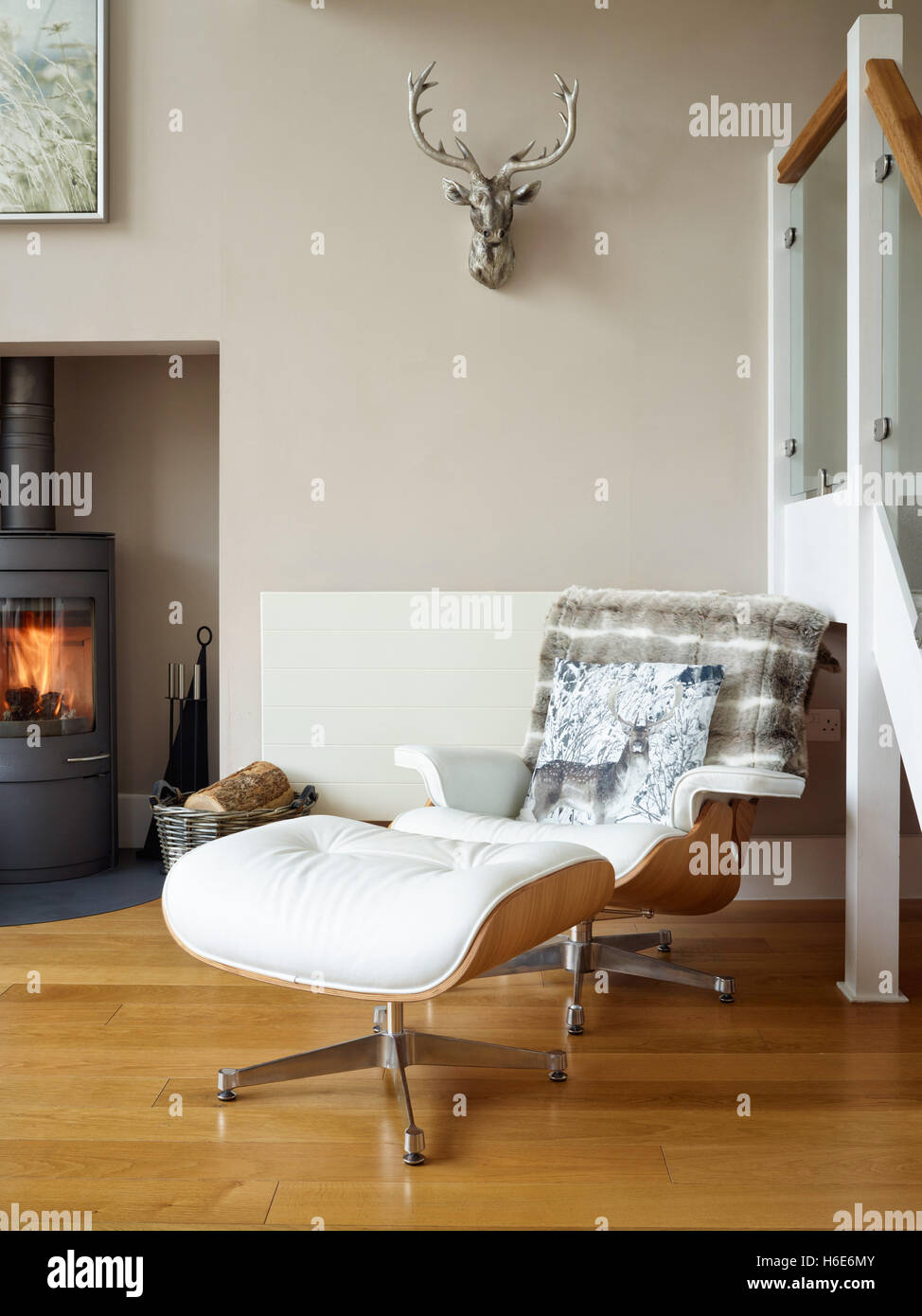 Un iconico stile Eames lounge in pelle Poltrona e poggiapiedi in un confortevole soggiorno con stufa a legna Foto Stock