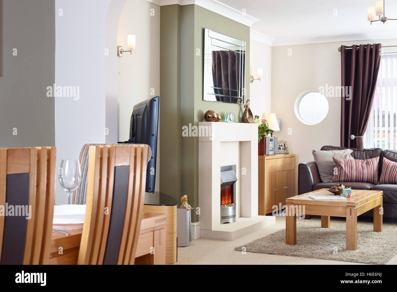 Un salotto aperto, sala da pranzo con caminetto e fuoco elettrico nella modernizzazione del Regno Unito home Foto Stock