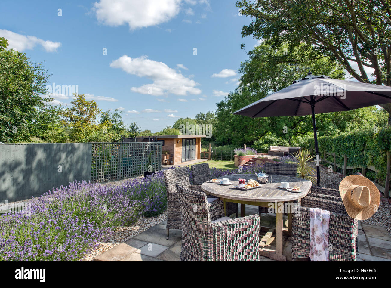 Un giardino inglese su una soleggiata giornata d'estate. Mobili da giardino, tabella impostata su Pronto per il tè del pomeriggio scones & Foto Stock