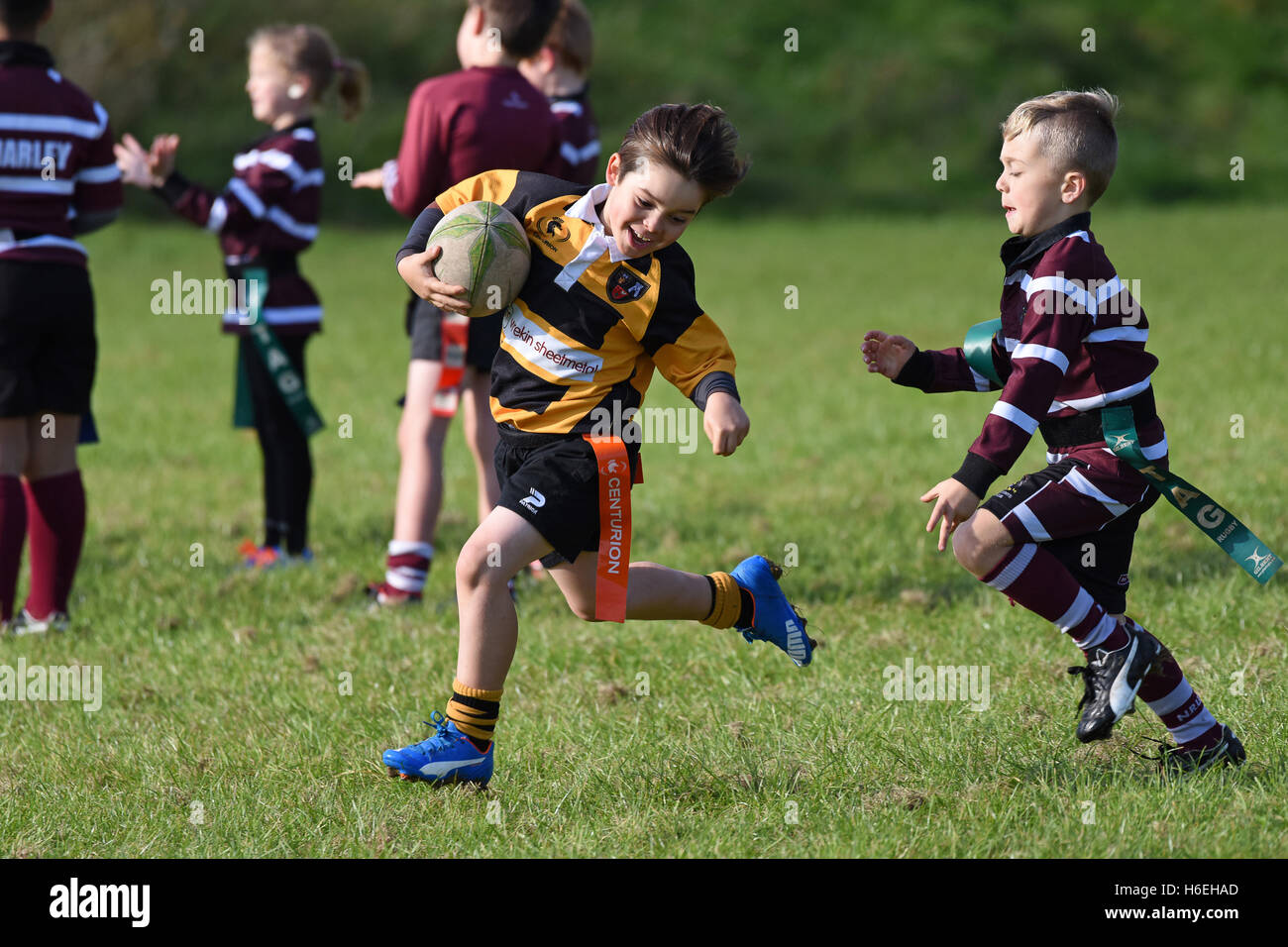 Ragazzo sorridente felice che gioca azione partita di rugby tag junior per bambini Regno Unito bambini bambini bambini sport attività sana sport ragazzi sport Foto Stock