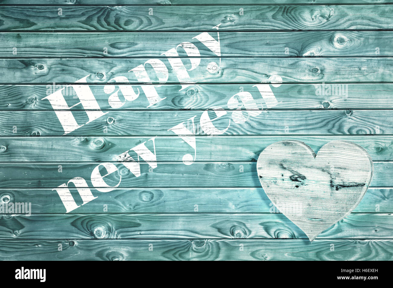 Felice anno nuovo dipinto in bianco su una tavola di legno di colore blu con pannello a forma di cuore Foto Stock