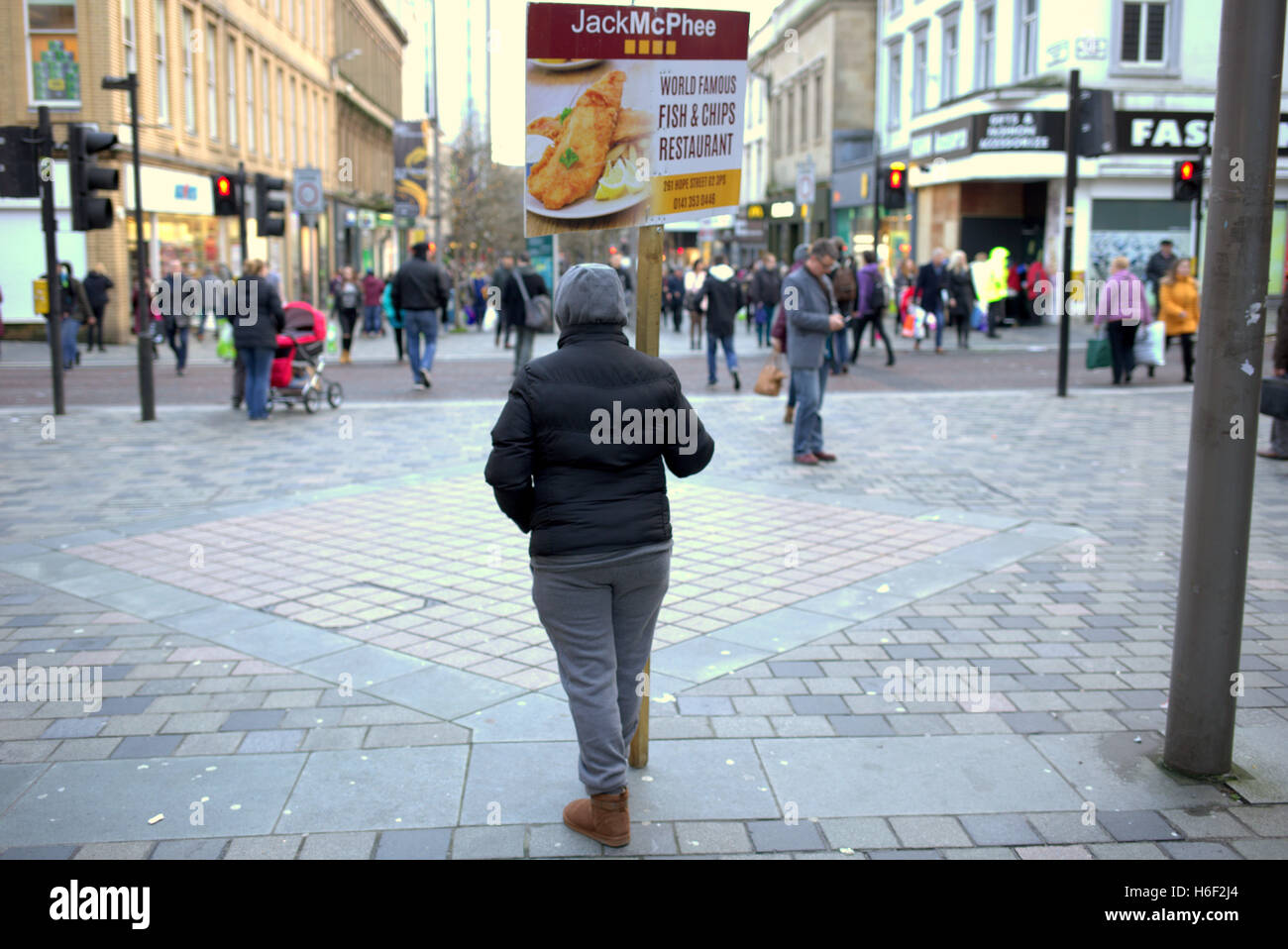 Panino tipo board street pubblicità pesce e patatine studente targhetta salario minimo lavoratore straniero Sauchiehall St marciapiede Foto Stock