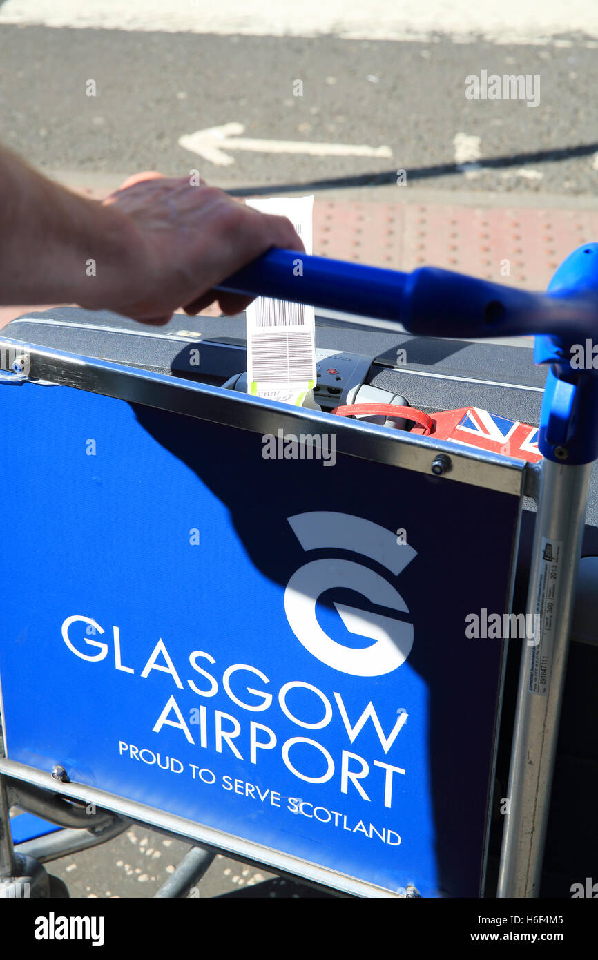 Spinta carrello bagagli all'aeroporto internazionale di Glasgow, Scotland, Regno Unito Foto Stock