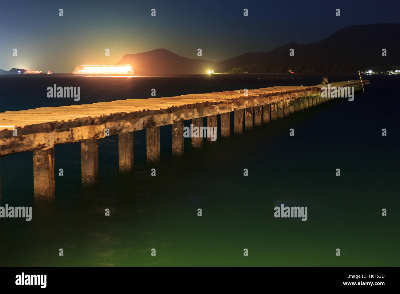 Casa in legno e il ponte in legno sul mare di notte con luce di colore Foto Stock