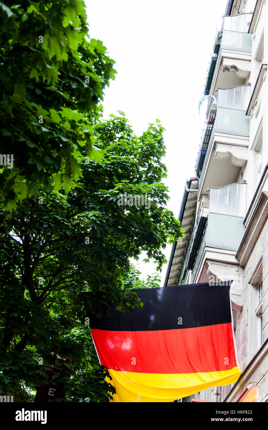 La Germania bandiera al di sopra di una strada di pavimentazione a Berlino Foto Stock