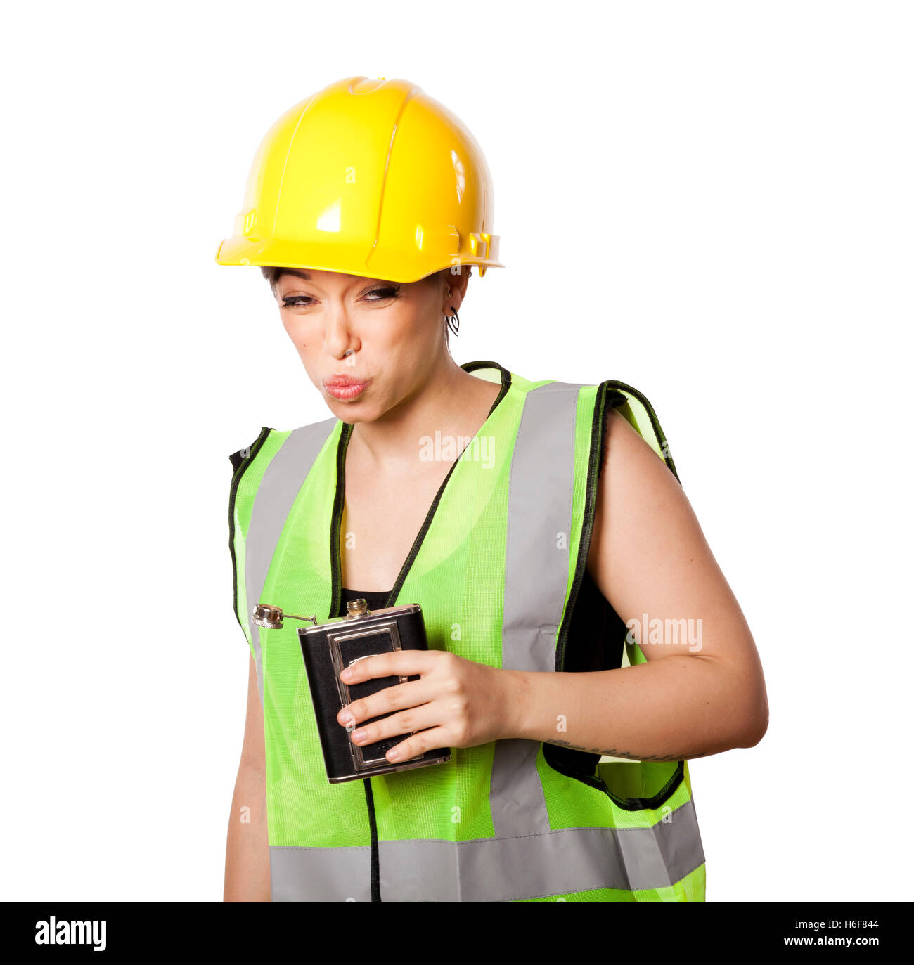 Giovani caucasici donna adulta nei suoi metà di 20s indossando riflettivo giallo casco di sicurezza e giubbotto di sicurezza, tenendo in mano una fiaschetta mentre ma Foto Stock