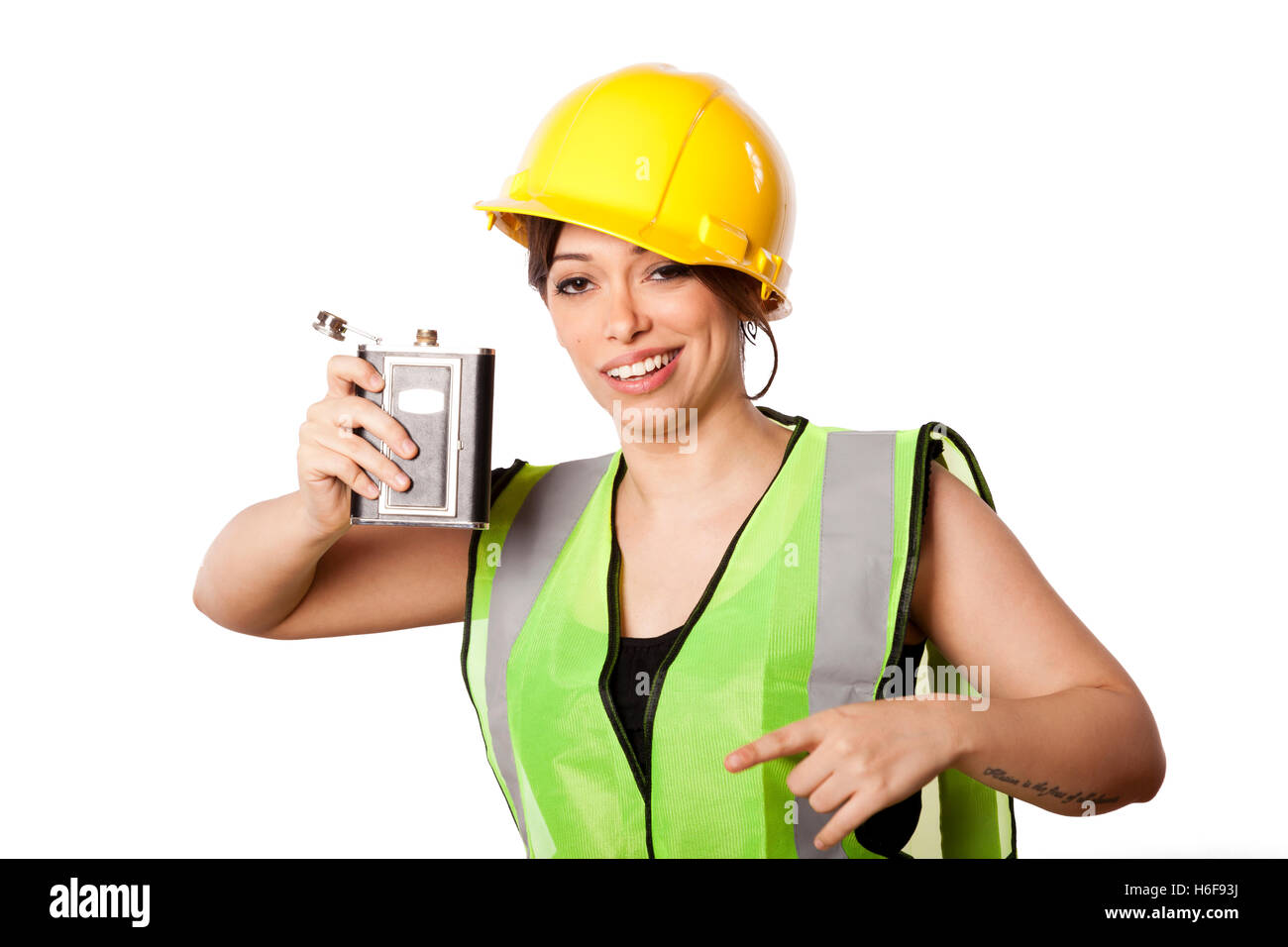 Giovani caucasici donna adulta nei suoi metà di 20s indossando riflettivo giallo casco di sicurezza e giubbotto di sicurezza, sollevando una fiaschetta mentre essere Foto Stock