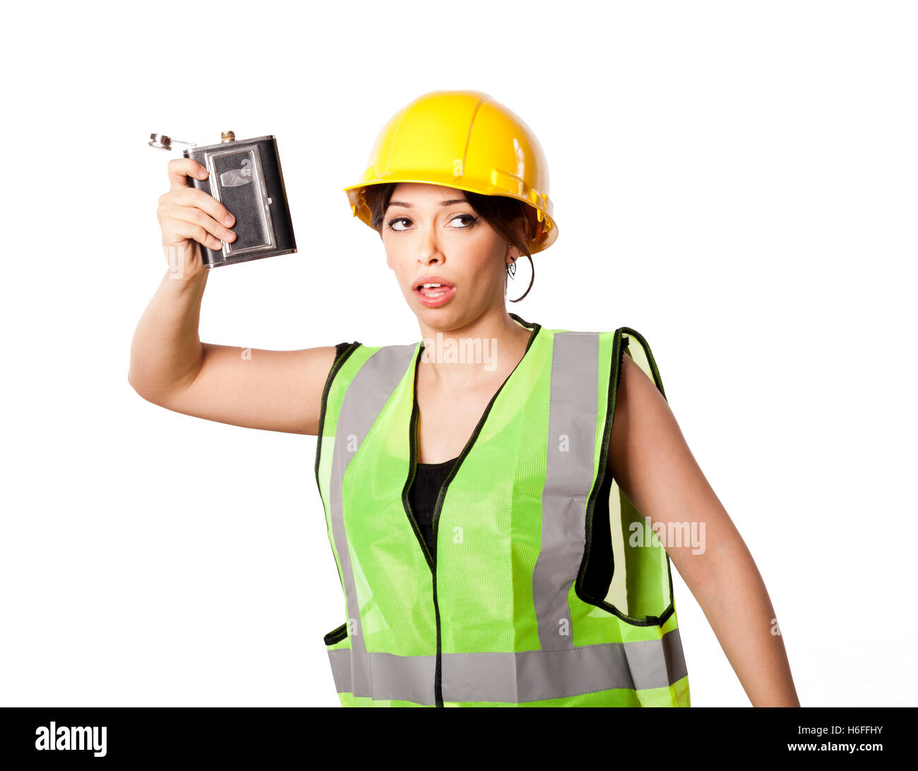 Giovani caucasici donna adulta nei suoi metà di 20s indossando riflettivo giallo casco di sicurezza e giubbotto di sicurezza, sollevando una fiaschetta mentre essere Foto Stock