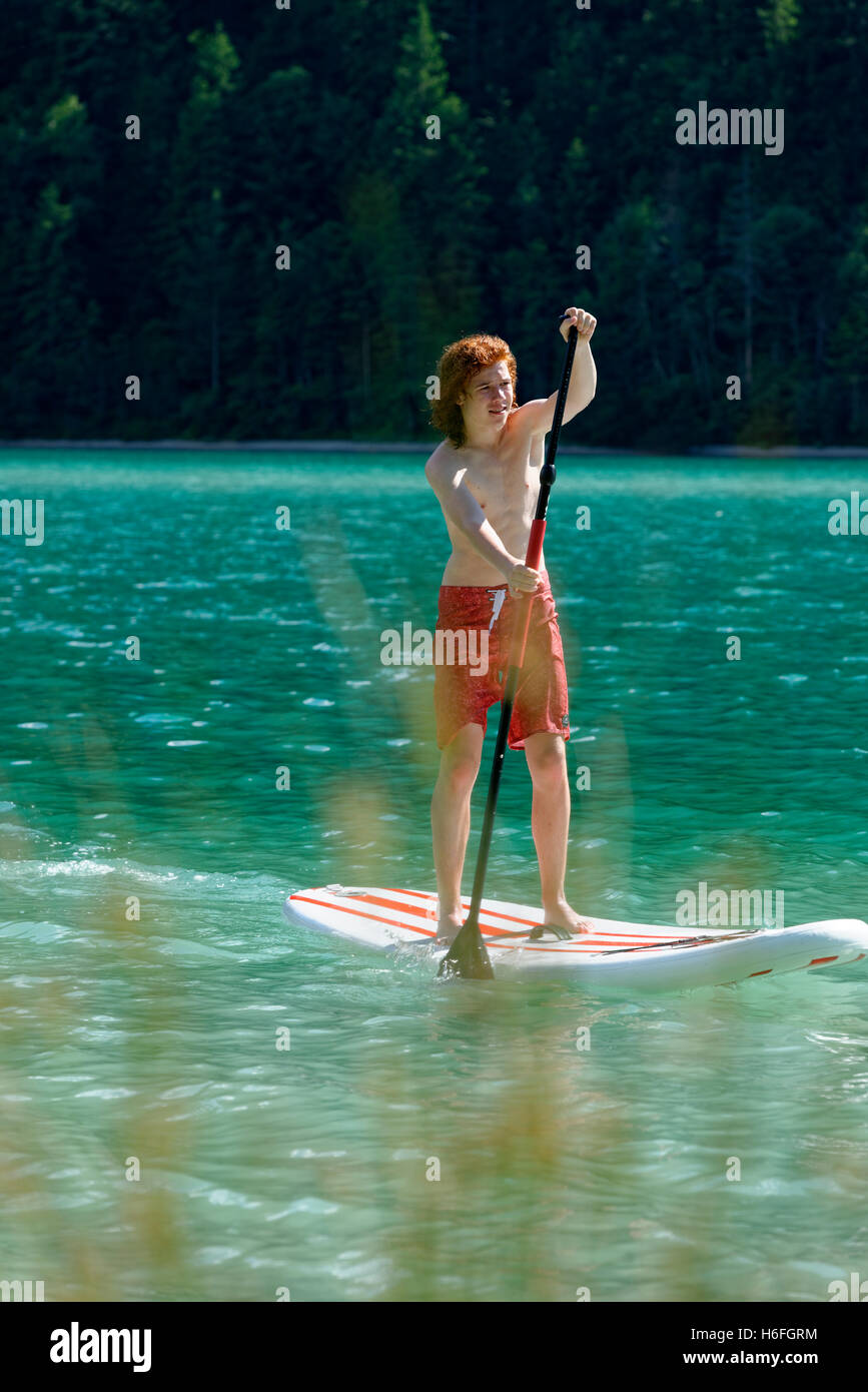 Adolescente, Paddleboarding, lago Plansee, Alpi Ammergau, Tirolo, Austria Foto Stock