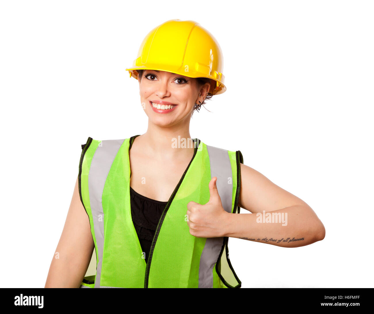 Giovani caucasici donna adulta nei suoi metà di 20s indossando riflettivo giallo casco di sicurezza e giubbotto di sicurezza" dando la telecamera il pollice Foto Stock