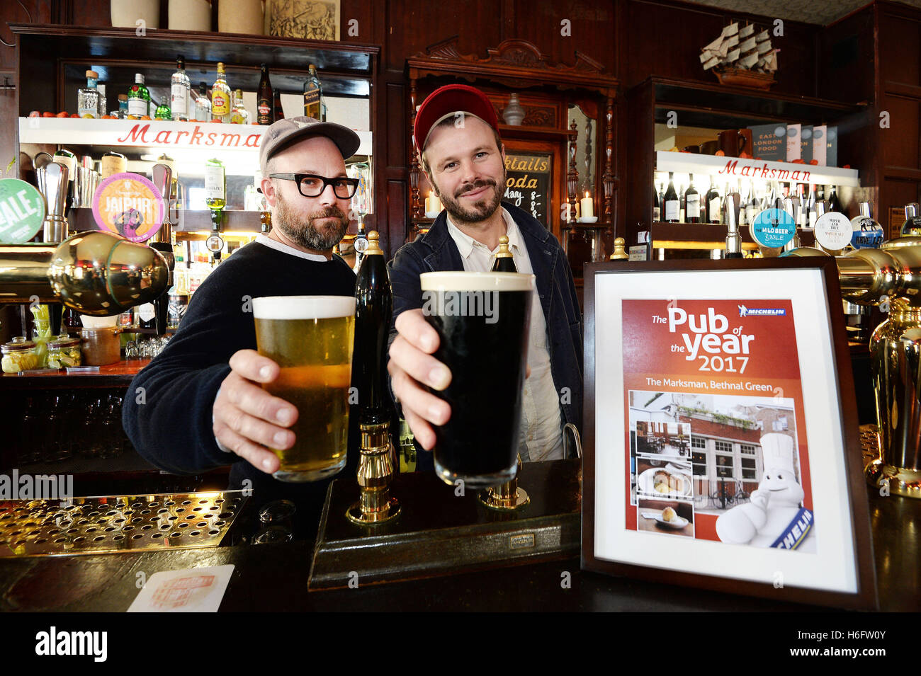 Tom Harris e Jon Rotherham (a destra), il co proprietari del tiratore scelto Pub di Hackney Road East London, toast il loro successo con una pinta di birra dietro il bar, dopo che esso è stato chiamato come la Michelin Pub dell'anno 2016. Foto Stock