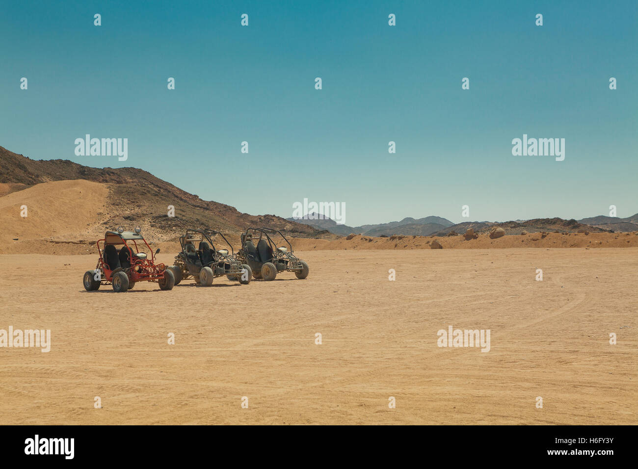 Tre atv in piedi nel deserto caldo sotto il cielo chiaro Foto Stock