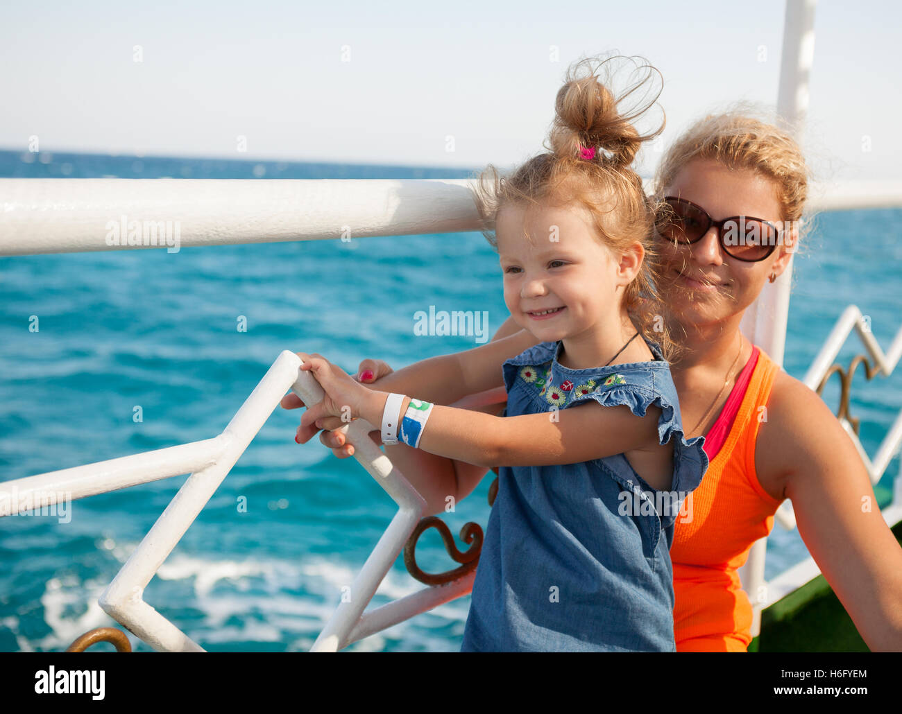 Bambina con la madre guardando il mare blu Foto Stock