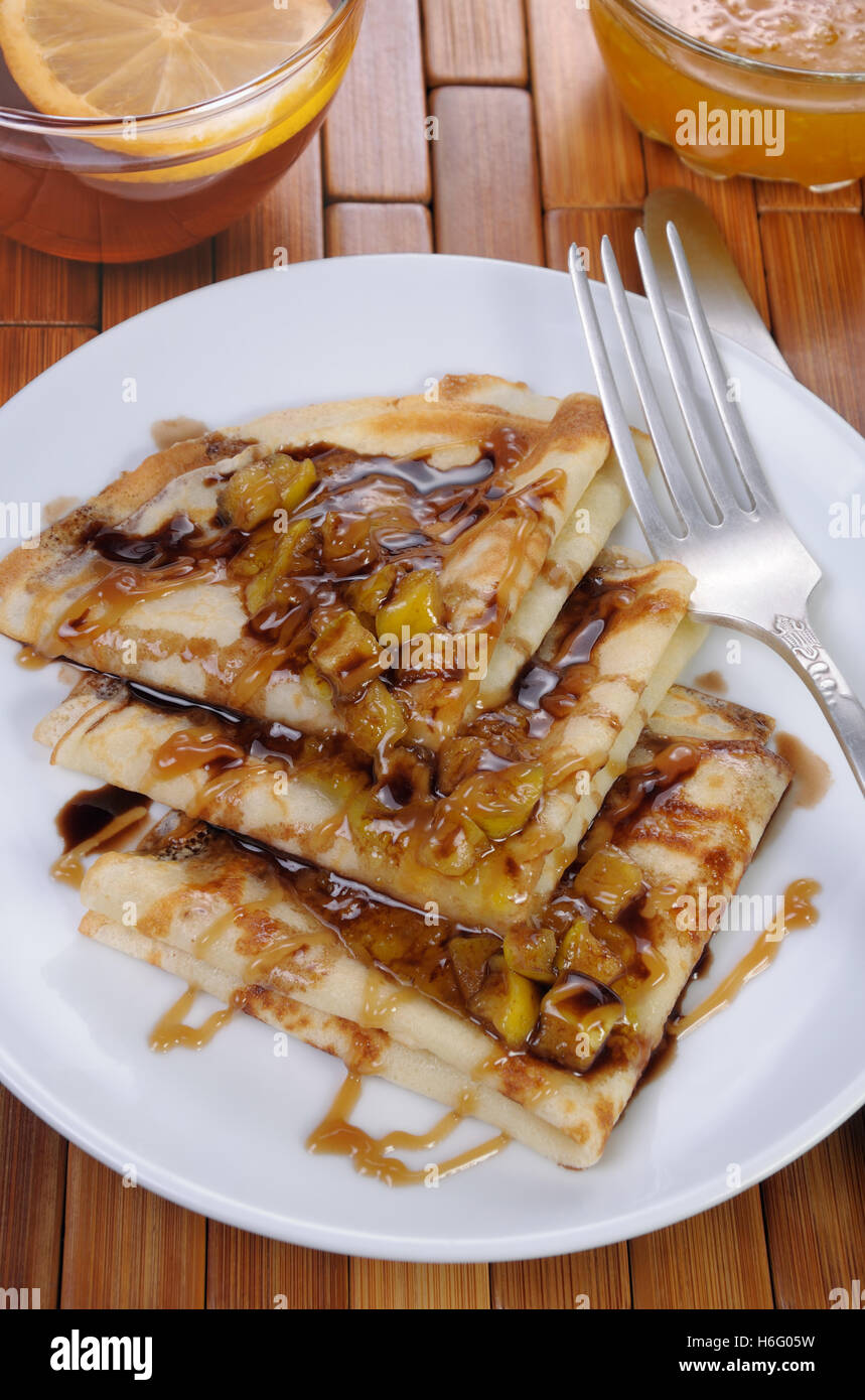 La colazione le frittelle su mele con caramello e cioccolato e la tazza di tè Foto Stock