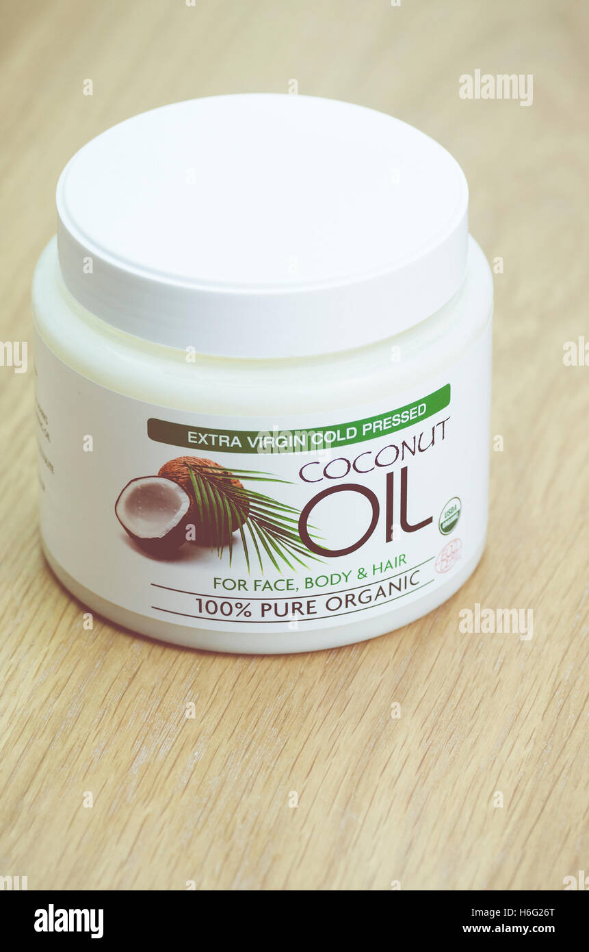 Olio di noce di cocco burro in un bianco può su di una superficie di legno - uno stile di vita sano Foto Stock