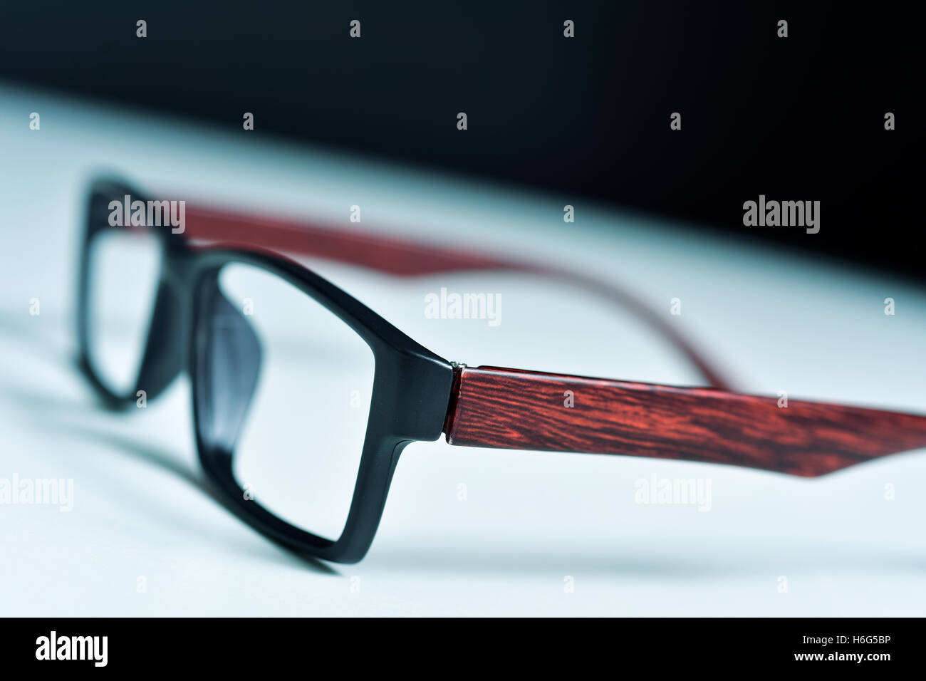 Primo piano di una coppia di legno e plastica occhiali bordati su una superficie bianca Foto Stock