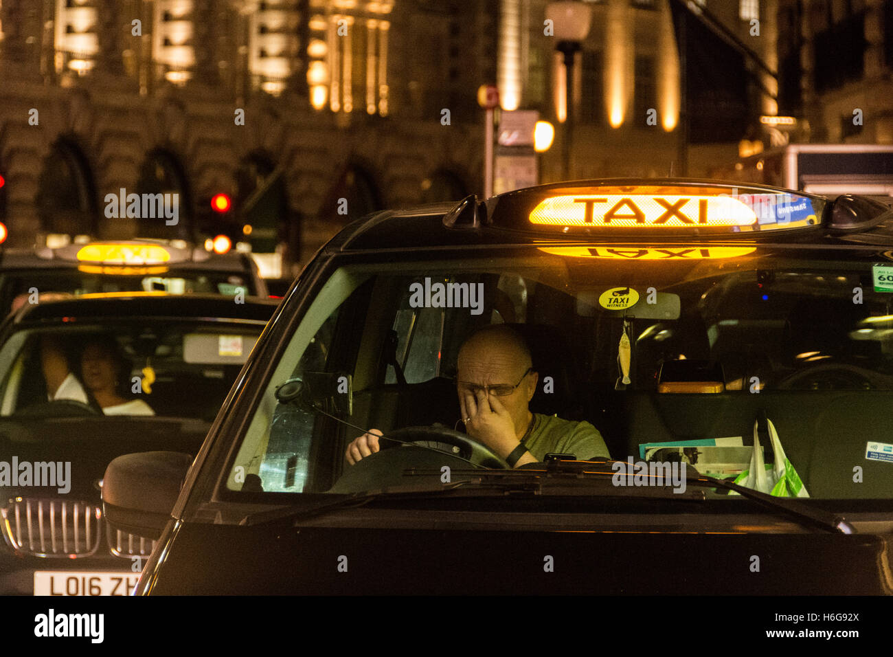 La fatica notturna si mostra sul volto di un tassista di Londra nel West End, Londra, Inghilterra, Regno Unito Foto Stock