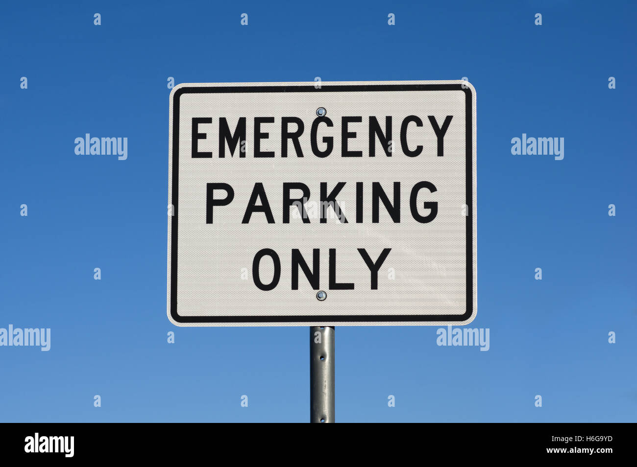 Il bianco e il nero di parcheggio di emergenza solo cartello stradale con cielo blu sullo sfondo Foto Stock