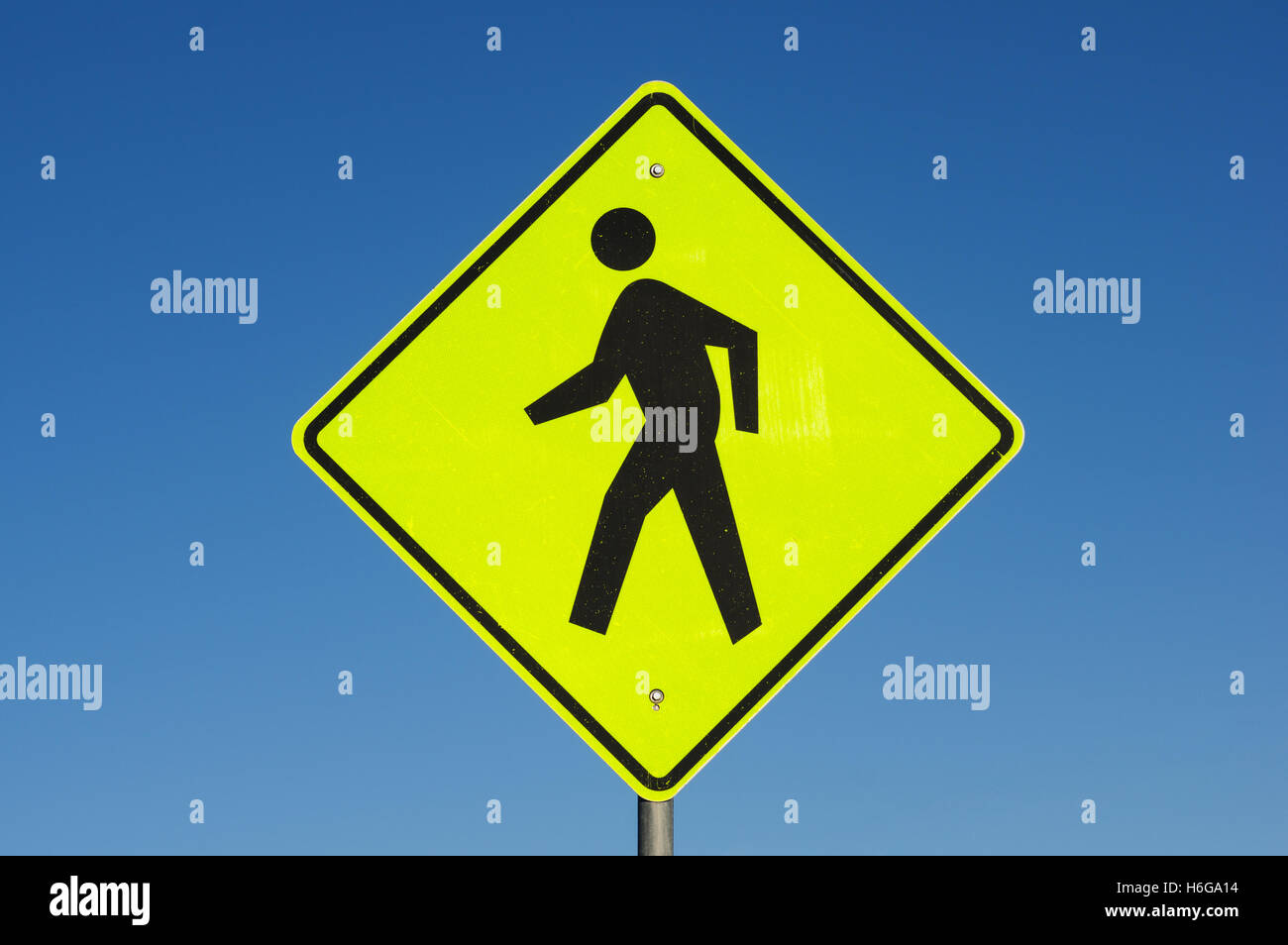 Il giallo e il nero attraversamento pedonale cartello stradale con cielo blu sullo sfondo Foto Stock