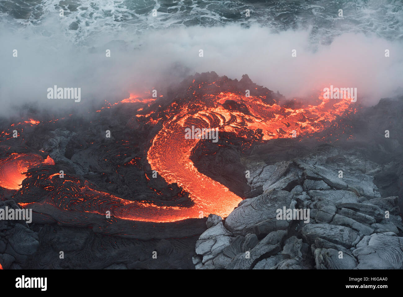 Un fiume di acqua calda di lava pahoehoe dal 61G flusso, emerge da un tubo di lava e si riversa nell'oceano all'oceano Kamokuna voce, un Foto Stock