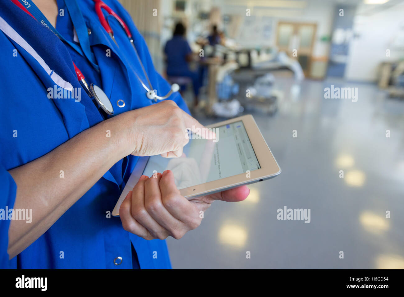 Un medico su una ward controlli a pazienti' registra su un Ipad Foto Stock