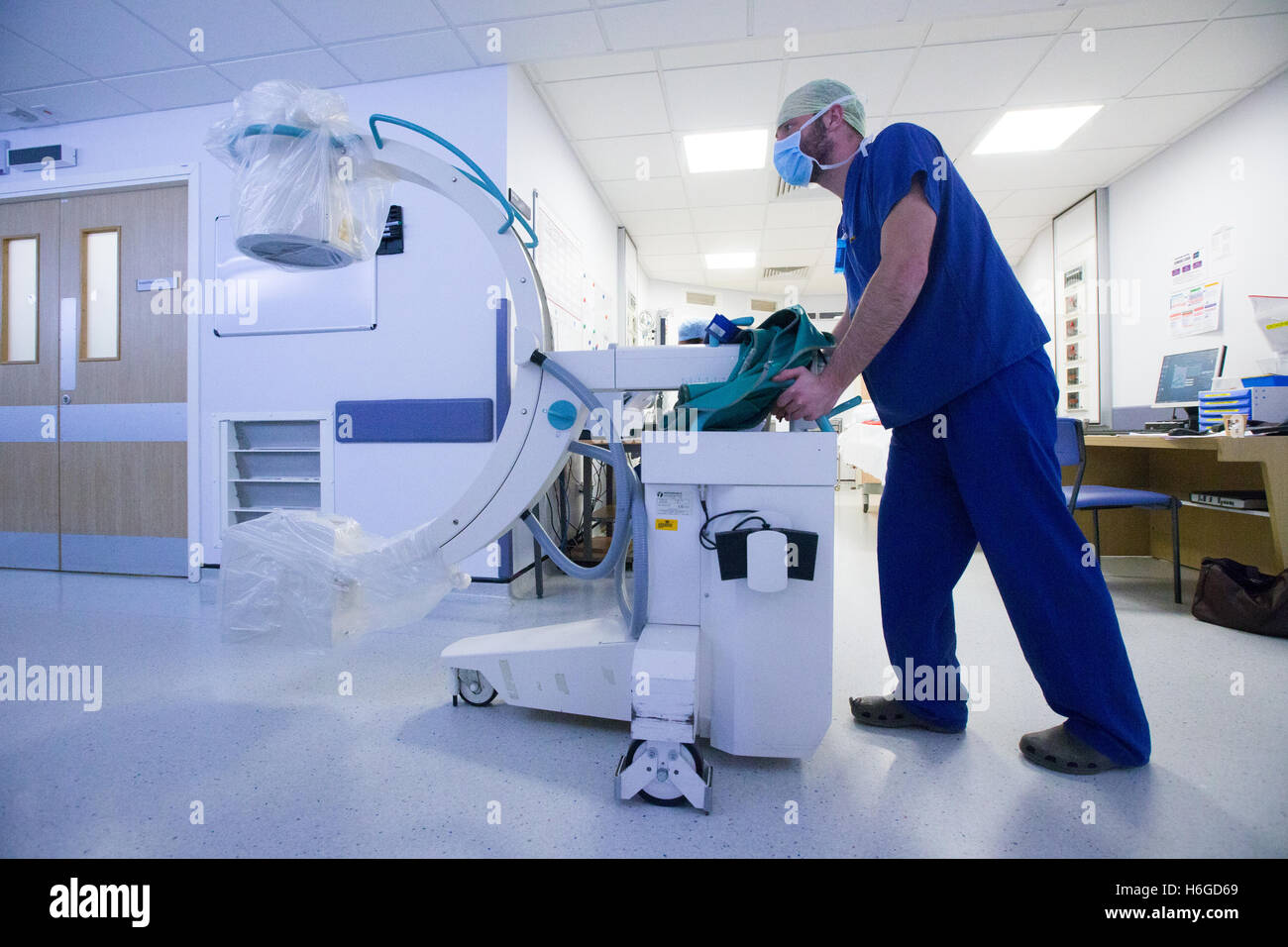 Un tecnico ospedaliero spinge un X Ray macchina lungo un corridoio Foto Stock