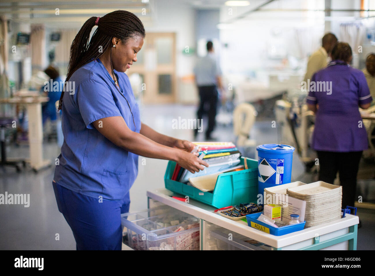 Un ospedale infermiere controllare le note sul paziente in reparto carrello Foto Stock