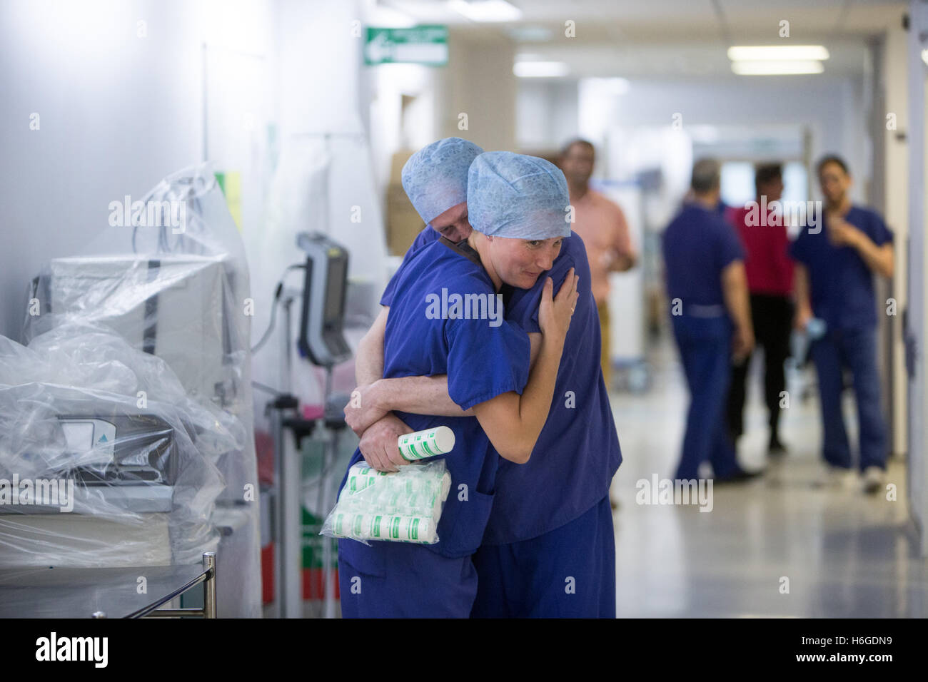 2 medici abbracciarsi in un ospedale di NHS corridoio dopo una operazione di successo Foto Stock