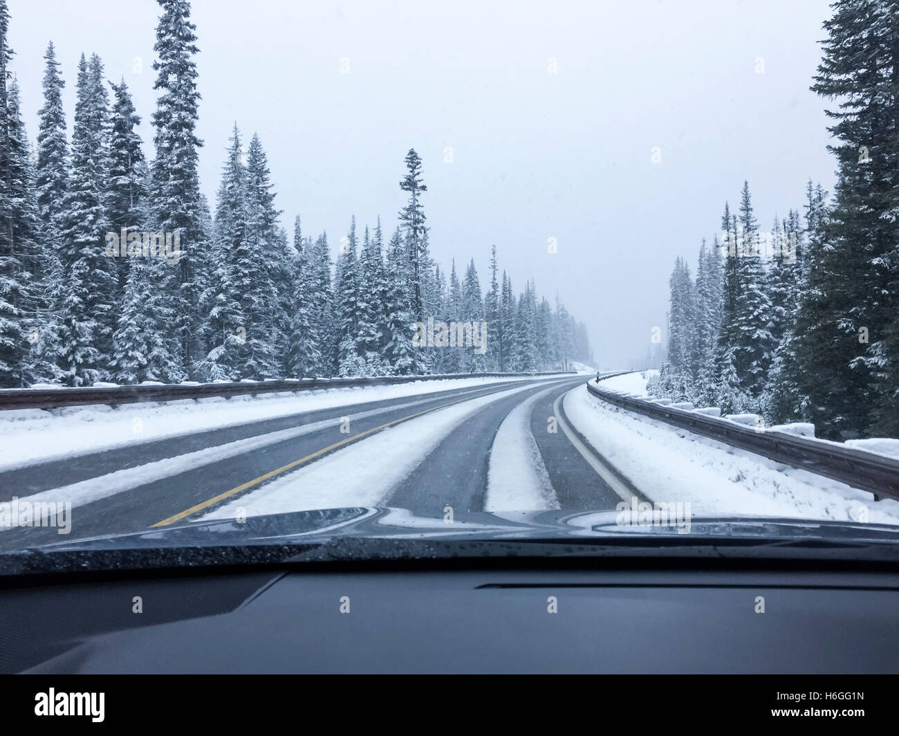 Conducente del punto di vista viewpoint guardando attraverso il parabrezza per auto vuoti di strada innevata in inverno la guida Foto Stock