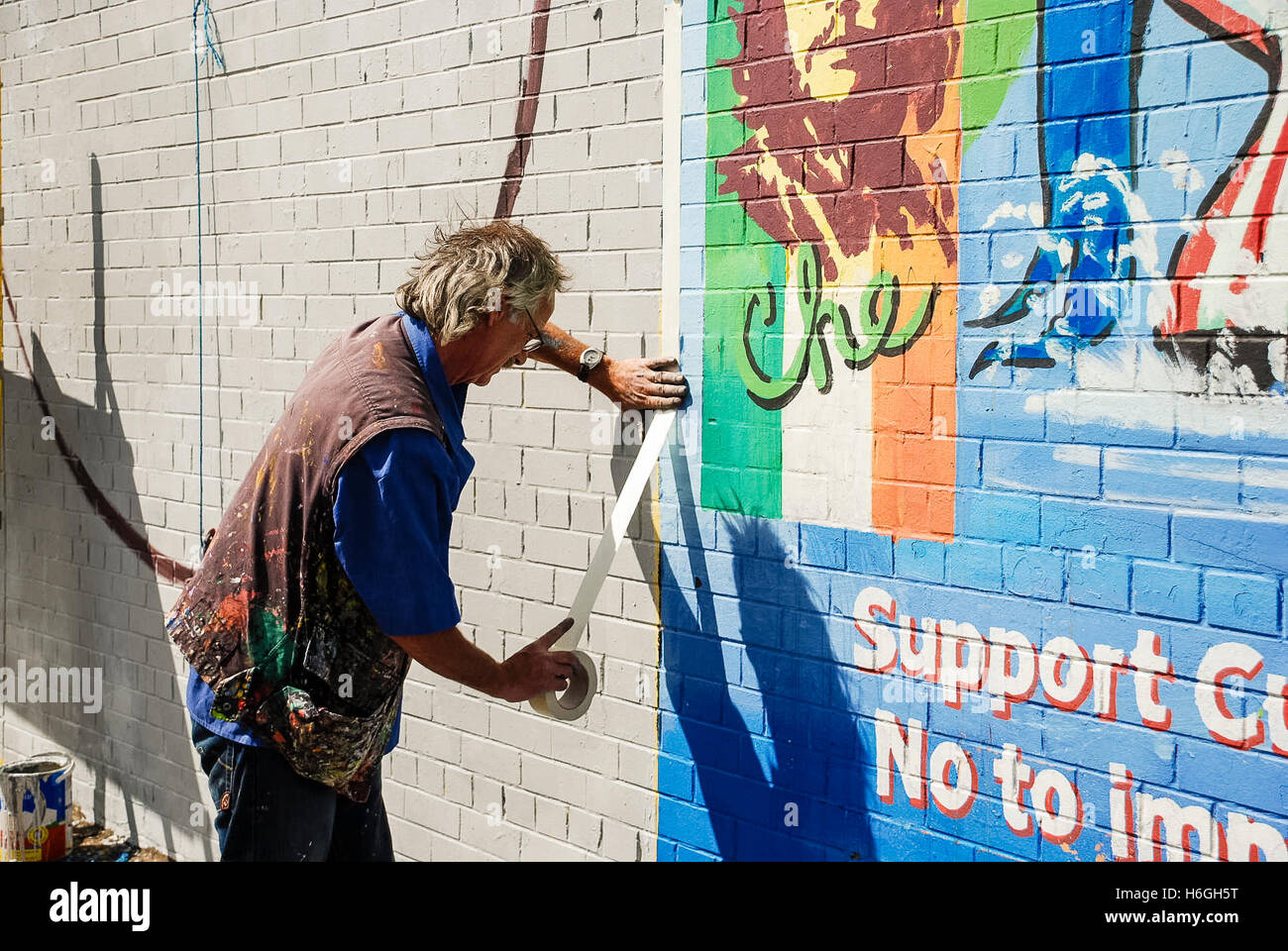 Artista Danny Devenney prepara una parete per un nuovo murale sulla pace internazionale a parete, Falls Road, Belfast. Foto Stock