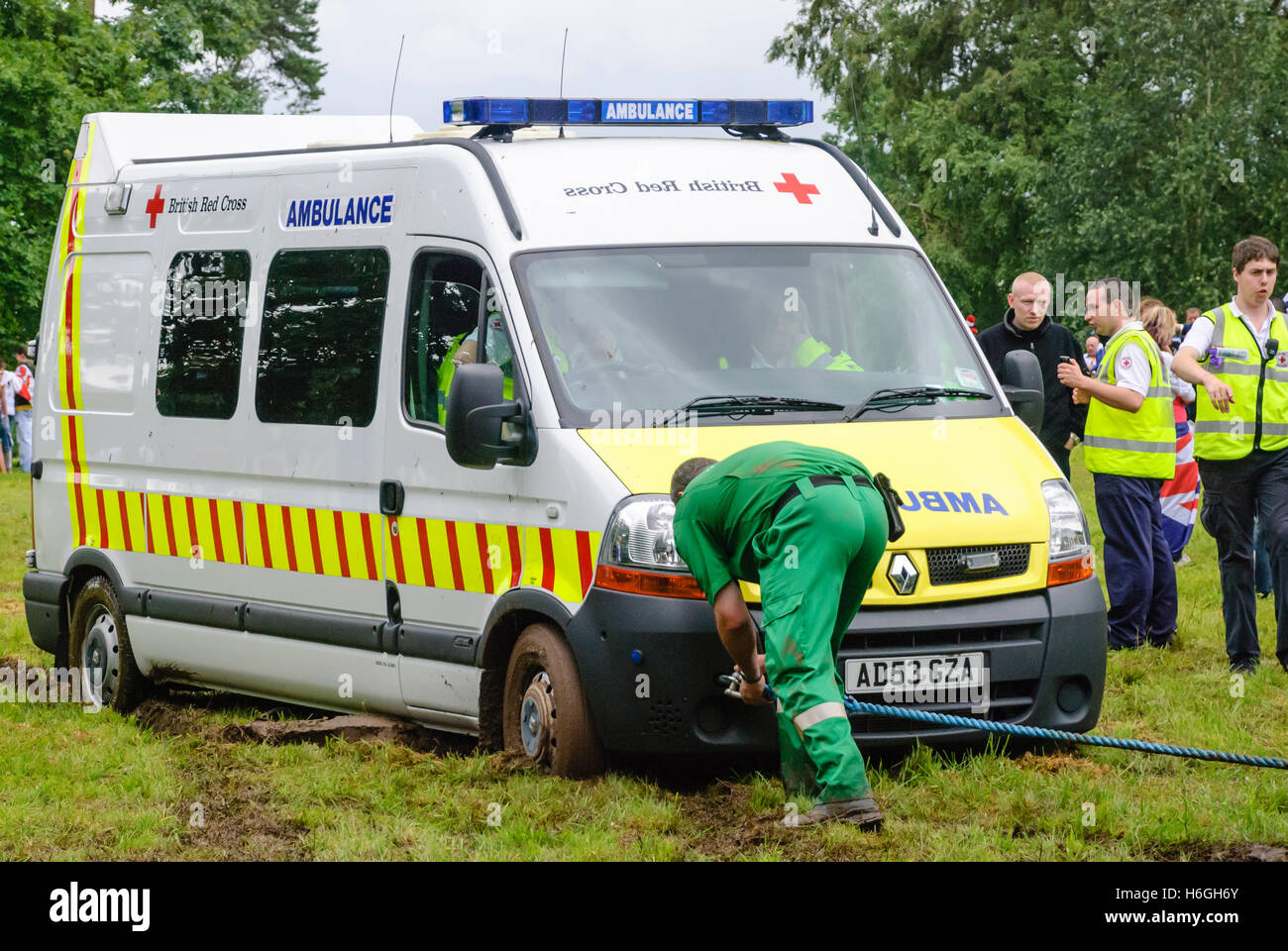 Paramedico attribuisce una fune di traino di un'ambulanza bloccata nel fango durante un festival Foto Stock
