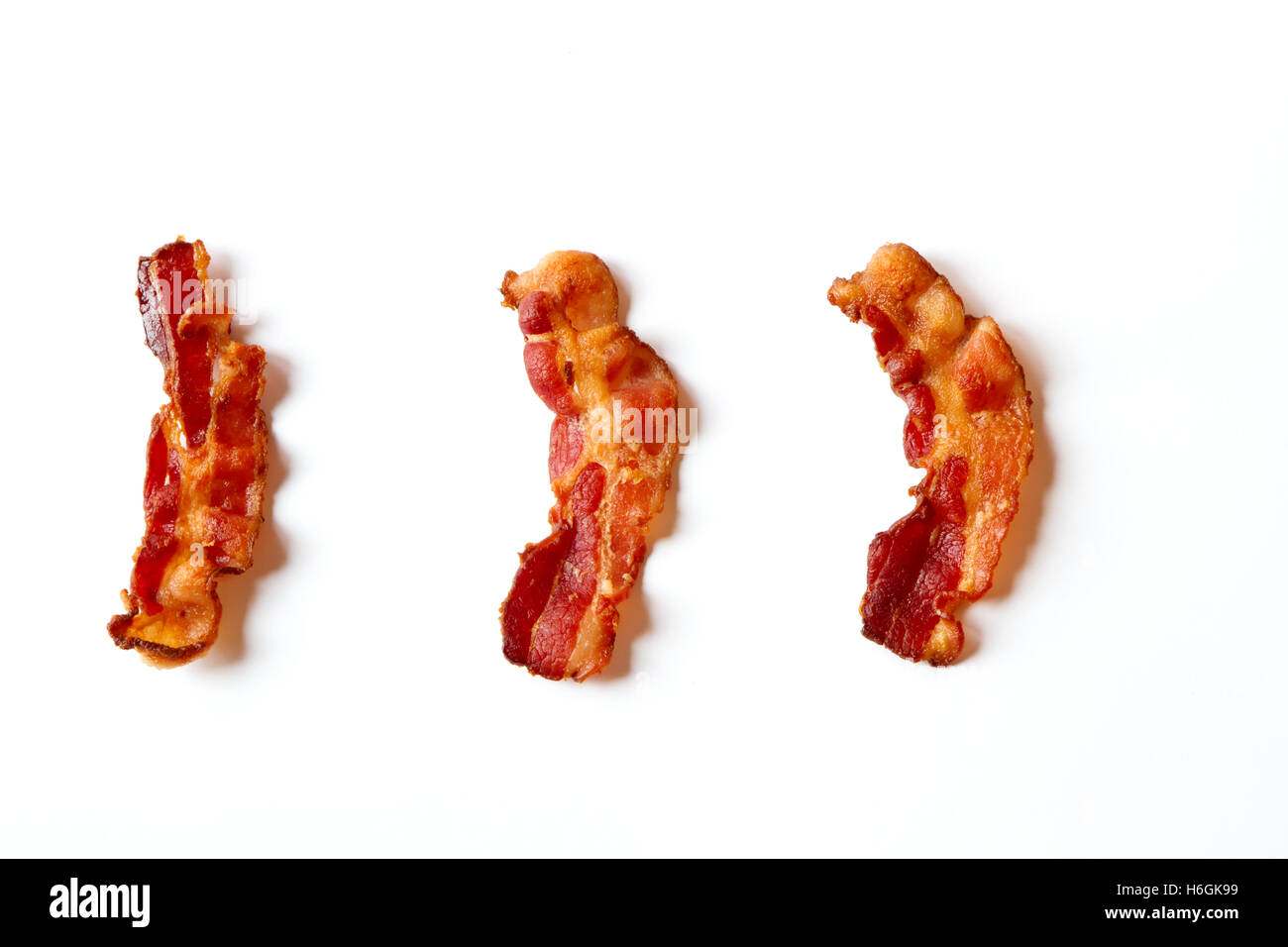 Tre fette di carni pancetta fritta allineate in una fila isolato su uno sfondo bianco Foto Stock
