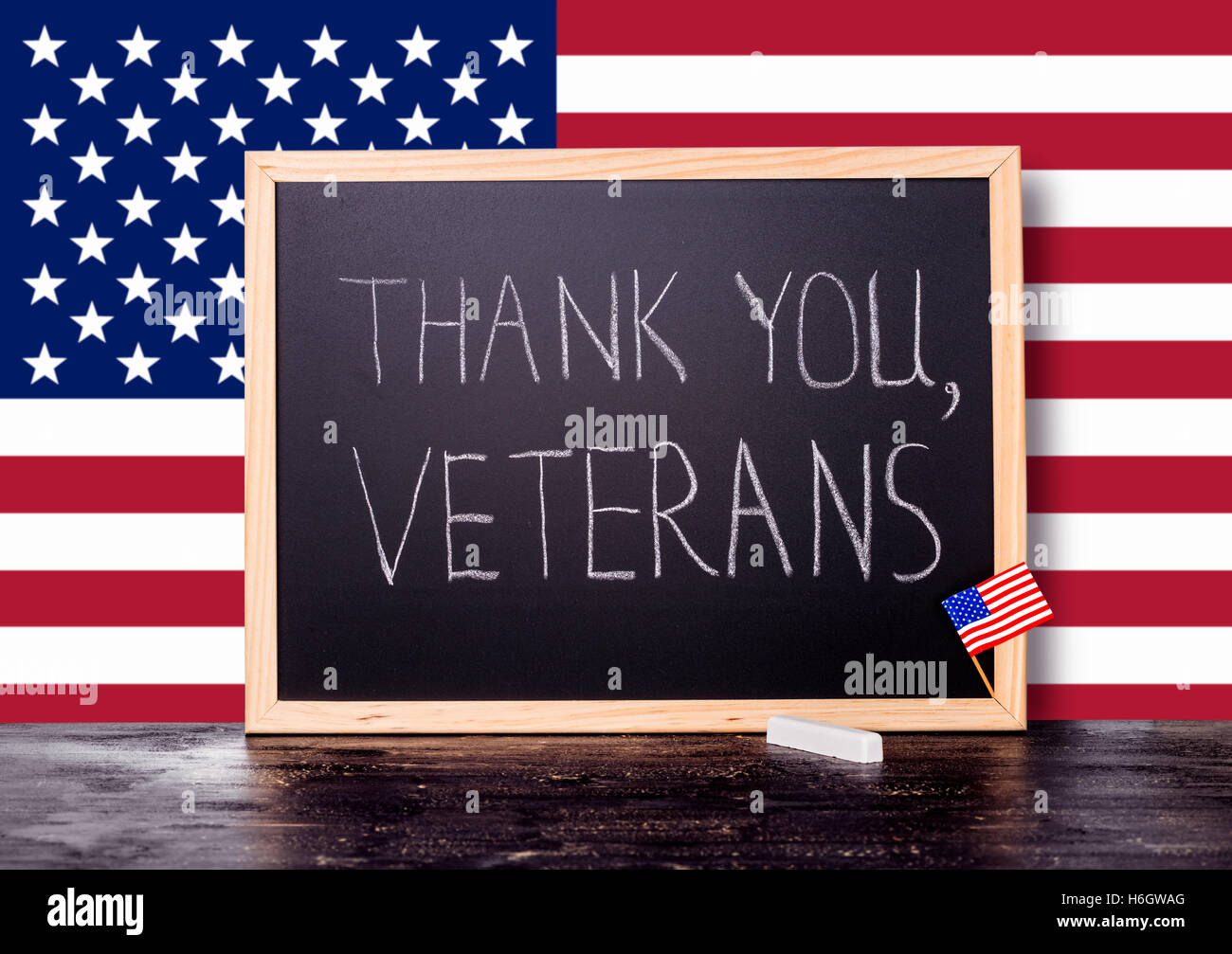 Biglietto di auguri del testo della scrittura grazie veterani è scritto in lavagna con bandiera degli Stati Uniti e del pezzo di gesso su craq Foto Stock