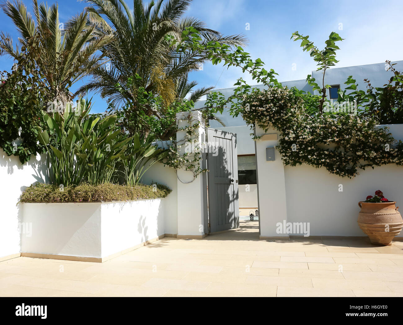 HERAKLION, Creta, Grecia - 13 Maggio 2014: cielo blu e aprire lo sportello sul terreno della villa con fiori, palme, anfore in hotel di lusso Foto Stock
