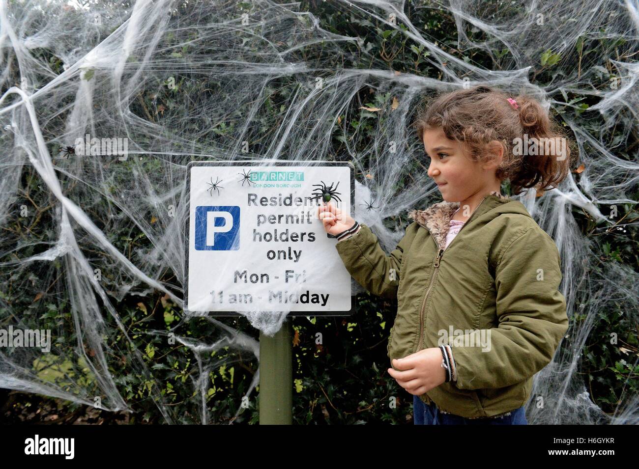 Cinque anni di Lily (cognome non dato) mette la rifinitura di un parcheggio decorato come segno di una strada nella zona nord di Londra si prepara per la festa di Halloween. Foto Stock