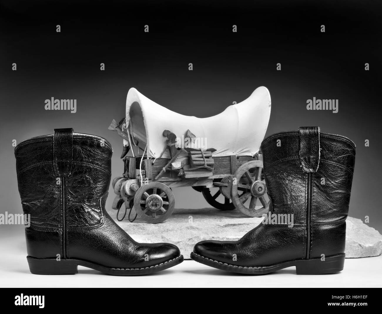 Kids cowboy stivali neri e Chuck wagon con una stanza per il tipo in bianco e nero. Foto Stock