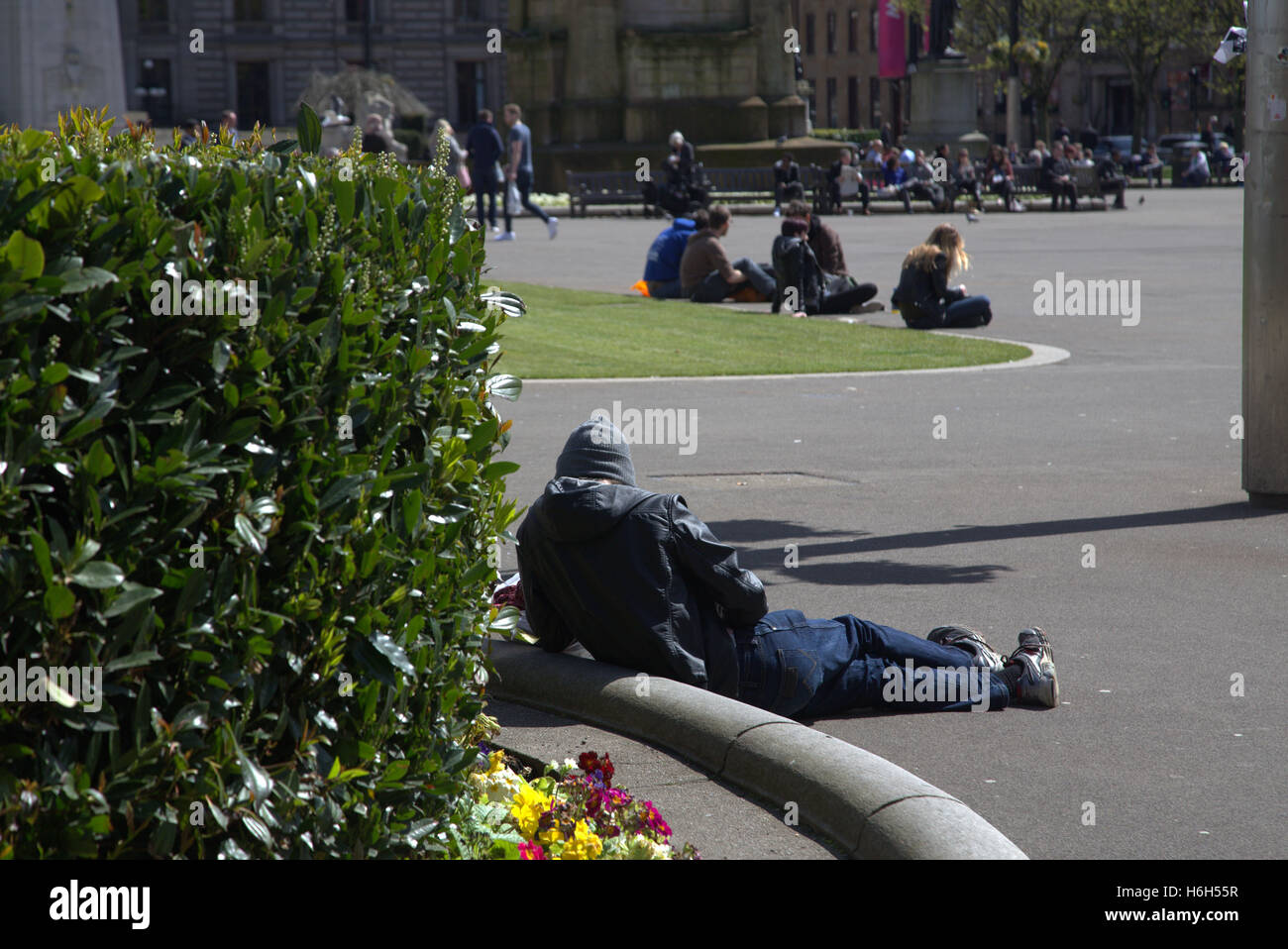 George Square nel centro della città di Glasgow Centre di gente del posto e turisti rilassatevi e godetevi il sole Foto Stock